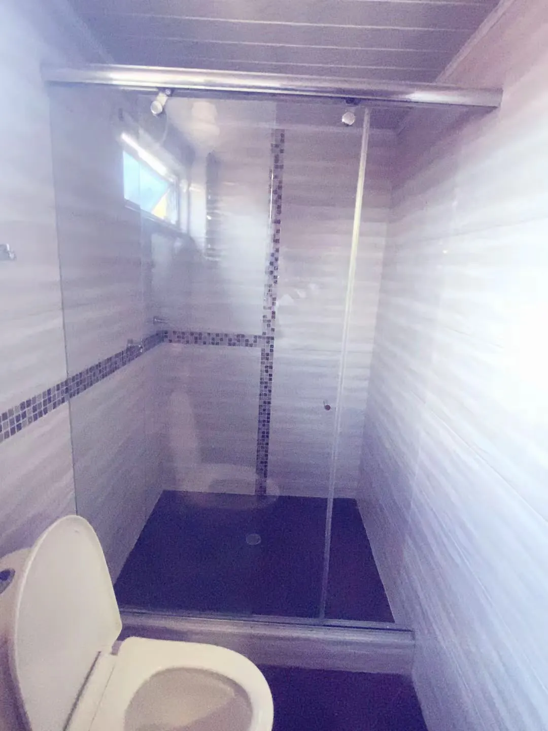 Baño privado con ducha de vidrio en Hospedaje Kiwi