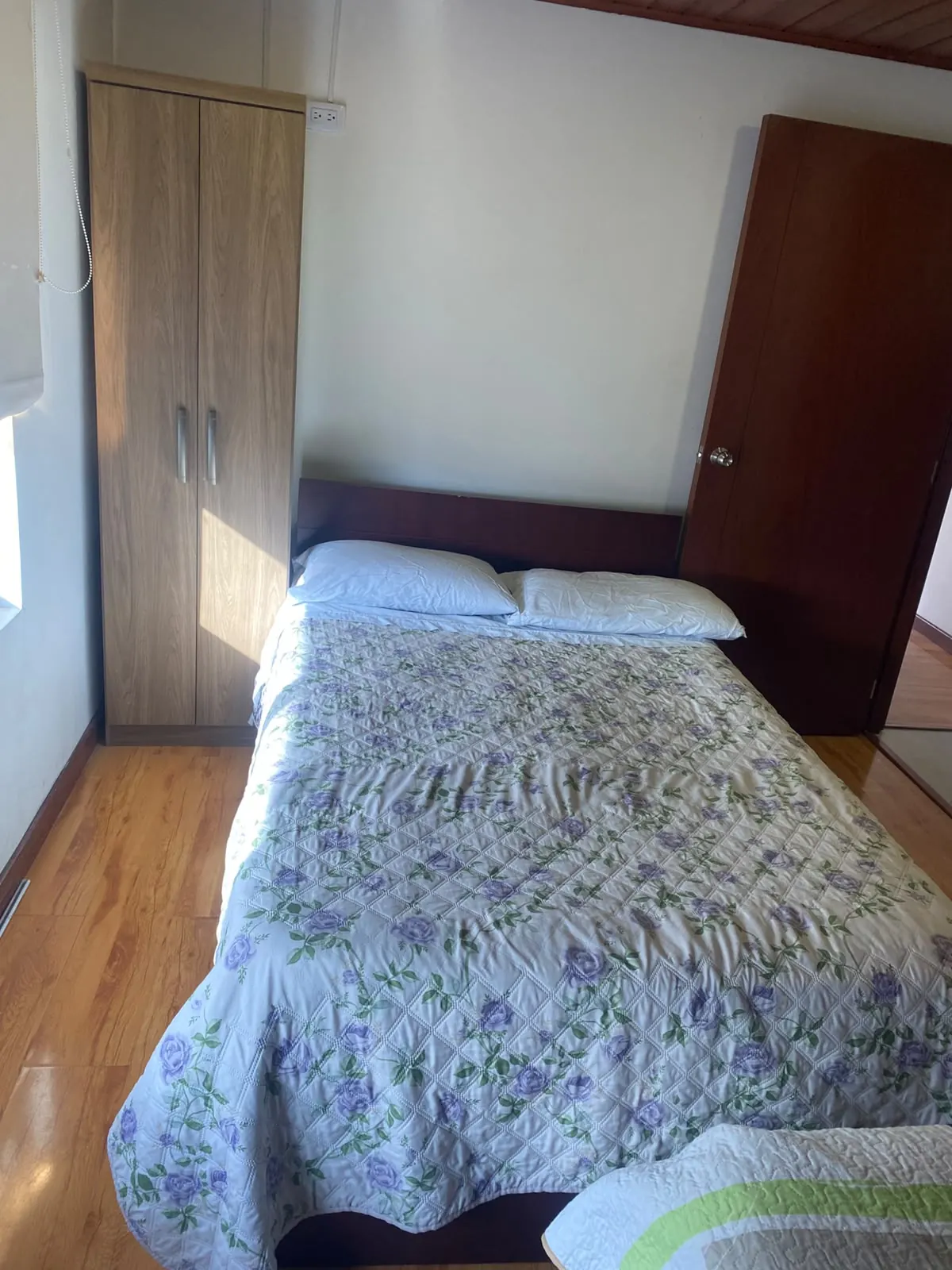 Habitación matrimonial con closet de madera y piso laminado en Hospedaje Kiwi